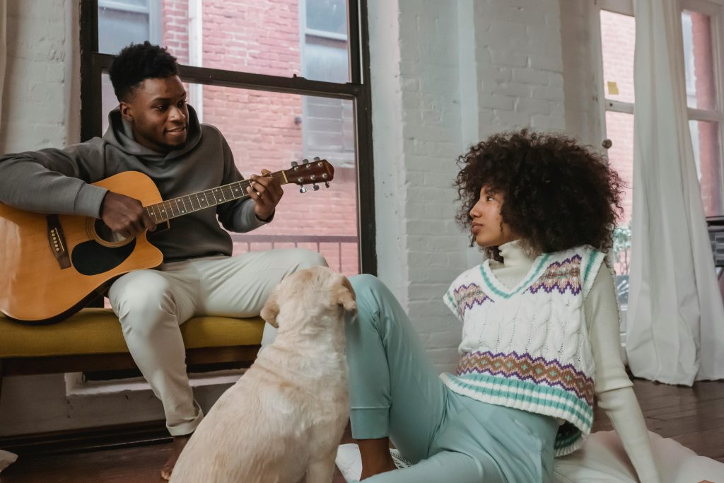 A loving couple enjoys music and companionship with their dog in a cozy living room.